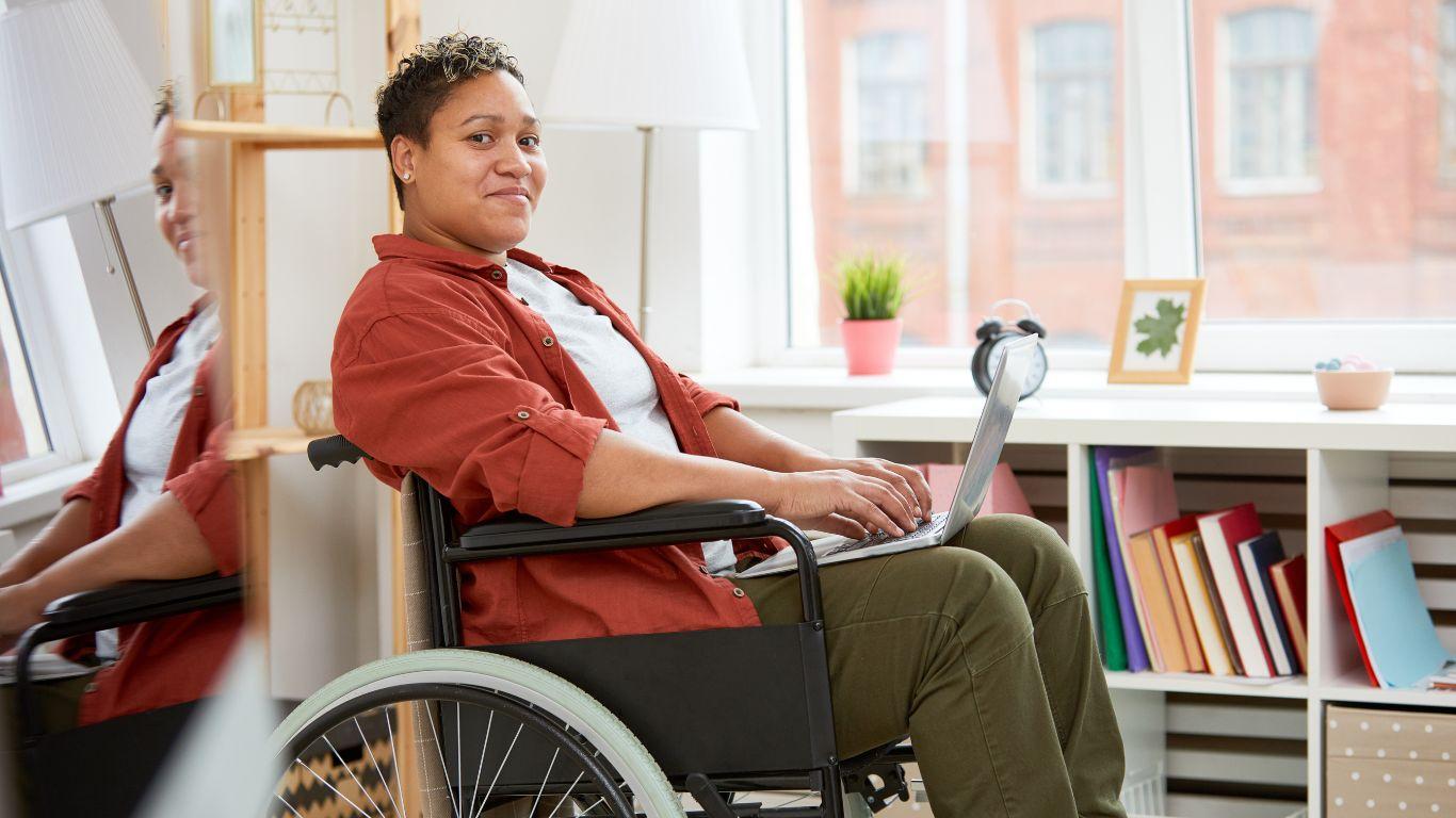Disabled person in wheelchair searching disability mortgages on a laptop